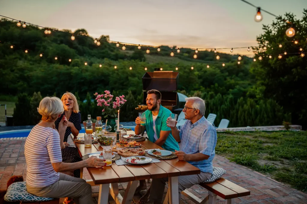 Una famiglia che cena in giardino al tramonto con tavola apparecchiata e atmosfera estiva