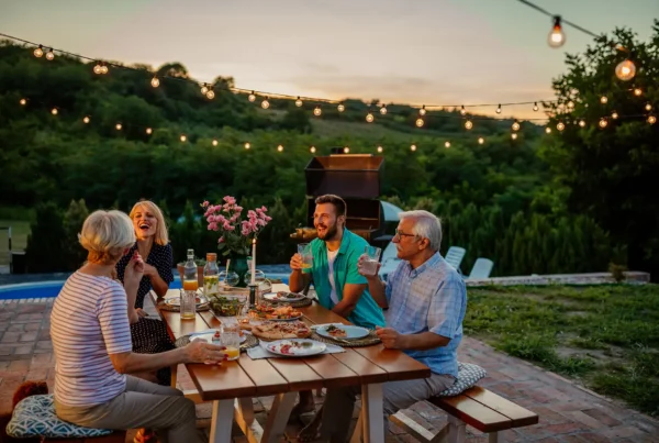 Una famiglia che cena in giardino al tramonto con tavola apparecchiata e atmosfera estiva